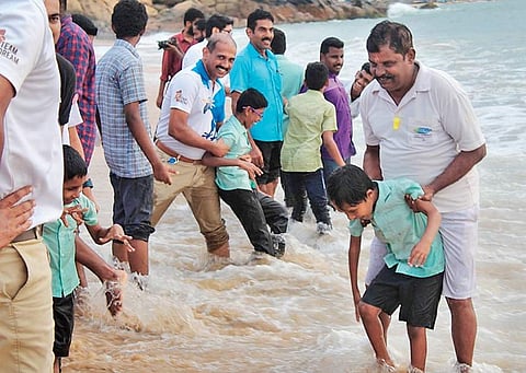 Volunteers along with children who are visually impaired enjoying the waves at Kovalam beach | EXPRESS