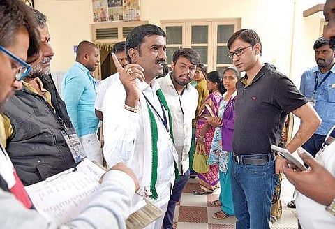 An observer interacts with Congress’ M Shivaraju about a snag in the EVM, at a polling booth in Mahalakshmi Layout | nagaraja Gadekal