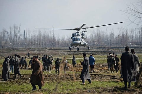 Indian soldiers and Kashmiri onlookers stand look on as an Indian army helicopter lands near the site where an Indian Air Force aircraft crashed. (Photo | AFP)