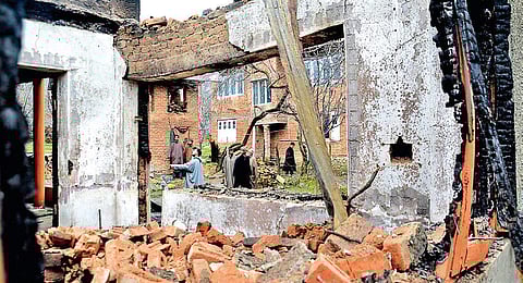 Villagers walk past the debris of a house destroyed after a gun battle between security forces and militants at Pinglish area of Tral in Pulwama district of Jammu and Kashmir on Monday | Zahoor Punjabi