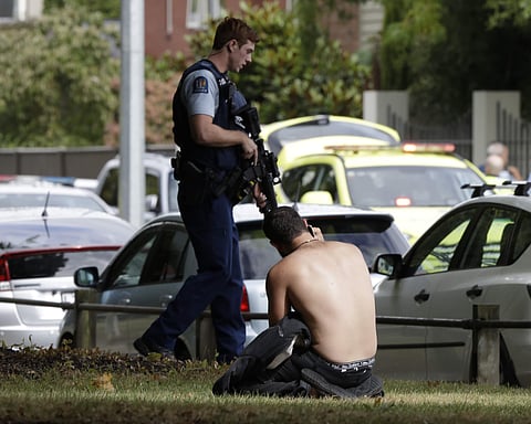 A man rests on the ground as he speaks on his mobile phone across the road from mosque in central Christchurch, New Zealand (Photo | AP)