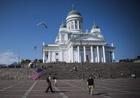 A man walks with a US flag at the Senate Square near the Presidential Palace where Russian and US Presidents meet for a summit in the Finnish capital Helsinki. (Photo | AFP)