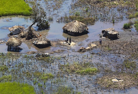 A family stand outside their submerged huts near Beira, Mozambique. (Photo | AP)