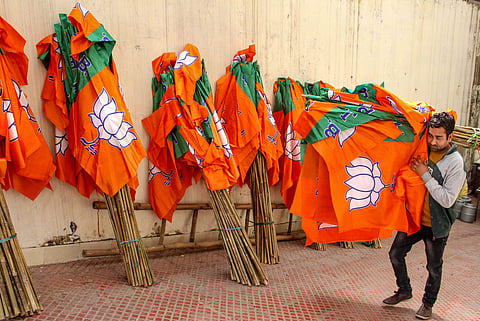 A worker carries Bharatiya Janata Party flags for distribution ahead of an election campaign in Jammu. (Photo | PTI)