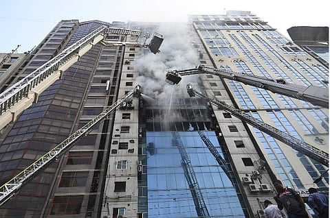 Bangladeshi firefighters on ladders work to extinguish a blaze in an office building in Dhaka on March 28, 2019. A huge fire tore through a Dhaka office block March 28 killing at least five people with many others feared trapped in the latest major infern