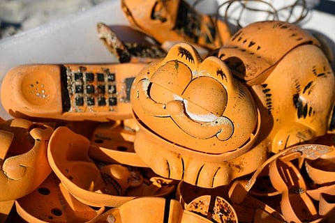 Spare parts of plastic 'Garfield' phones are displayed on the beach on March 28, 2019 in Plouarzel, western France, after being collected from a sea cave by environmental activists. (Photo: AFP)