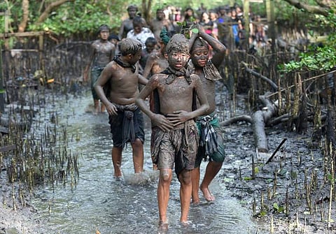 Balinese people put mud on their body during a traditional mud bath known as Mebuug-buugan, in Kedonganan village, near Denpasar on Indonesia's resort island of Bali. (Photo | AFP)