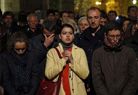 People pray as Notre Dame cathedral burns in Paris. (Photo | AP)