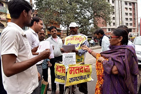 In this file taken on March 26, 2019, Lal Mani Das is seen handing out voting information pamphlets to prospective voters in Patna. (Photo | AFP)