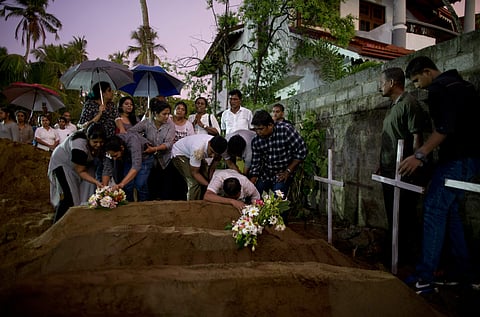 Relatives place flowers after the burial of three victims of the same family, who died at the bombings in Sri Lanka (Photo| AP)