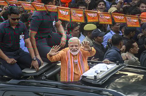 Prime Minister Narendra Modi waves at supporters during his roadshow a day ahead of filing his nomination papers for the Lok Sabha polls in Varanasi. (Photo | PTI)