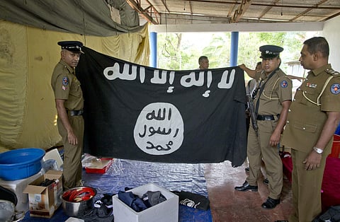 Police officers display a flag in Arabic that reads: 'There is no god, but Allah' and 'Of Allah is the Prophet, Muhammad' in Ampara in Sri Lanka on Sunday (AP photo)