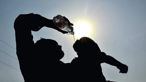 A man gives water to his child on a hot summer day in Hyderabad
