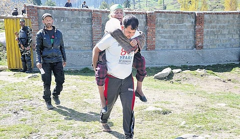 An elderly, riding piggyback on a youth, arrives to cast her vote at a booth in Kulgam district of Jammu and Kashmir on Monday | zahoor Punjabi