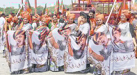 BJP supporters wearing sarees with PM Narendra Modi’s portrait, pose for a photo in Surat, on Thursday | PTI