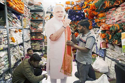 Workers attend to a cut-out of India's Prime Minister Narendra Modi in a store selling election merchandise at the Sadar Bazaar market in New Delhi. (Photo | Ruhani Kaur, Bloomberg)