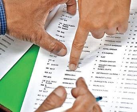 A voter checks the voters list at a polling station at Rajinder Nagar on Sunday. | (Naveen Kumar | EPS)