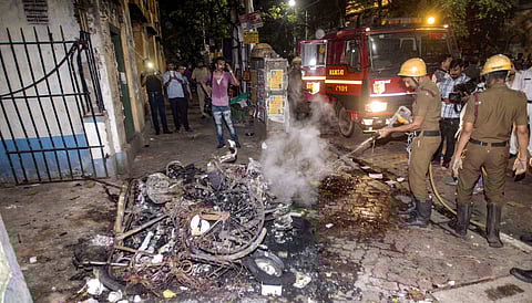 Firefighters douse burning vehicles caused by a mob during BJP President Amit Shah's election roadshow in Kolkata (Photo | PTI)