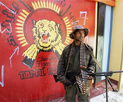Sri Lankan Army soldier stands guard in an abandoned building, as the logo of LTTE is seen in the background, in Mullaittivu. (File | AP)