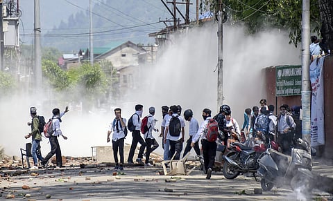 Srinagar college students pelt stones at policemen amid tear gas during a protest against the alleged rape of a three-year-old girl by a local in Bandipora. (Photo | PTI)