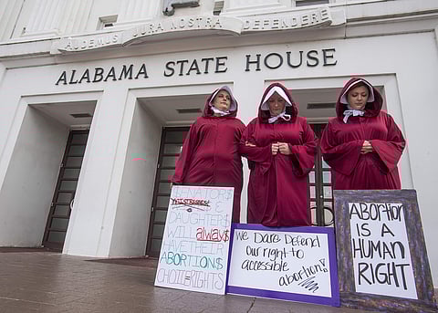 Three women, dressed as handmaids, protest against a bill banning nearly all abortions at the Alabama State House in Montgomery (File Photo | AP)
