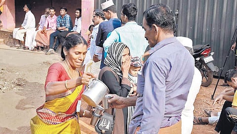 A woman gives water to a voter outside booth number 48 at the Kinanur-Karinthalam grama panchayat in the Trikaripur Assembly segment, one of the booths where reepolling was held on Sunday