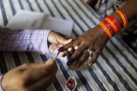 A polling officer puts indelible ink mark on the index finger of an women voter at a polling station. (Photo | AP)
