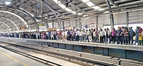 Passengers wait at the Chhatarpur station for metro service to resume; (Inset) technicians on the repair work | pARVEEN NEGI