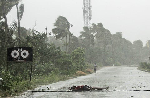 A farmer lies on the road after falling while crossing the road due to gusty winds ahead of the landfall of cyclone Fani on the outskirts of Puri, in Odisha. (Photo | AP)