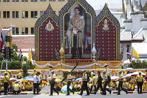 First aid workers walk pass a portrait of King Maha Vajiralongkorn during a series of his coronation ceremonies Sunday in Bangkok. (Photo | AP)