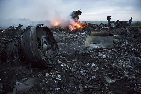 In this Thursday, July 17, 2014 file photo, a man walks amongst the debris at the crash site of a passenger plane near the village of Hrabove, Ukraine. (Photo | AP)
