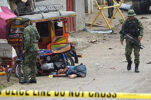 Soldiers walk past the body of a man slumped beside a tricycle following an armed attack in front of the temporary headquarters of the army's First Brigade Combat team, in Jolo on the southern island of Mindanao on June 28, 2019. (Photo | AFP)