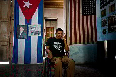 A man poses next to Cuban and US flags at his home, with the Cuban one carrying photos of Fidel and Raul Castro, in Havana, Cuba (File Photo | AP)