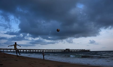 As the dark rain clouds hovering in the skies forming the background kids play football in Valiyathura beach in Thiruvananthapuram. | (BP Deepu | EPS)