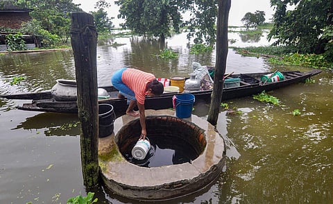 A woman collects potable water from a well in the flood affected area of Rajabari village. (Photo| PTI)