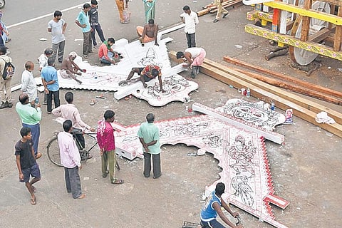 Temple artisans drawing the panel comprising ‘Duar Ghoda’ and ‘Rahu Pati’ that will be attached to the chariots, on the Grand Road on Monday. ( Photo | Ranjan Ganguly)
