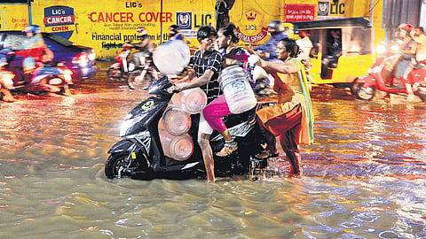 People on way to fetch water through waterlogged General Patters Road in the city on Tuesday. (Photo | Debadatta Mallick, EPS)