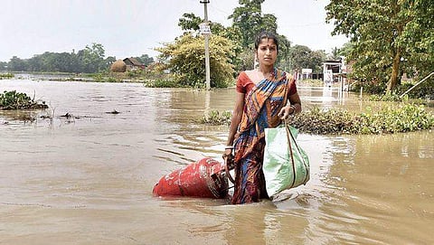 A woman carries her belongings from a flood affected area to a safer place, following heavy monsoon rain in Morigaon district of Assam on Friday (File photo | PTI)