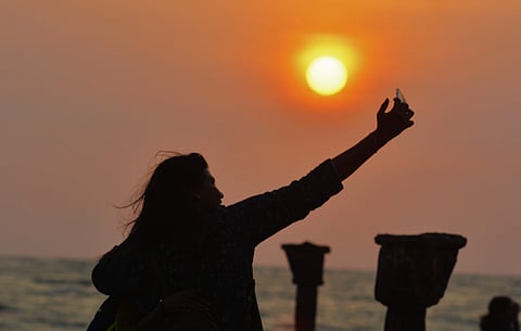 A woman takes a selfie against the backdrop of the setting sun. (Photo | Manu R Mavelil, EPS)