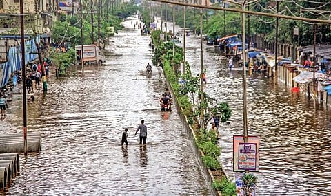 People walk on waterlogged railway tracks owing to heavy rains at Tilak Nagar Station in Mumbai on Tuesday | PTI