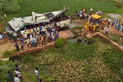 People look on at the mangled remains of a bus after it skidded off the six-lane Yamuna Expressway and fell into a large drain near Agra on 8 July 2019. (Photo | PTI)