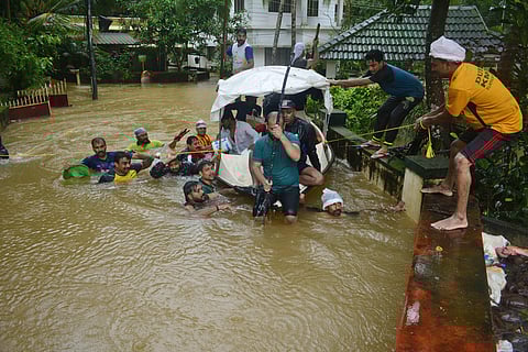 Youngsters struggling to move the boat in the heavy force of flood water at Cheruvatta in Kozhikode. | (Manu R Mavelil | EPS)