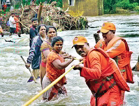NDRF personnel rescuing flood-hit people at Ranni Kurumbanmuzhi causeway. | (Shaji Vettipuram | EPS)