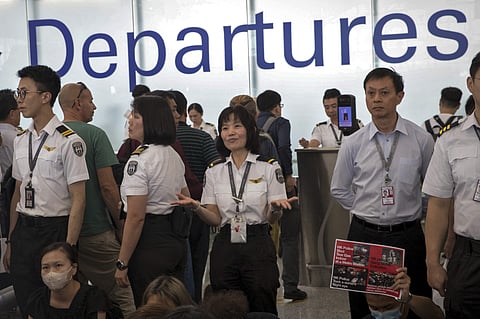 An airport security staff member gestures to travelers at the Hong Kong International Airport in Hong Kong, Tuesday, Aug. 13, 2019. | ( Photo | AP )