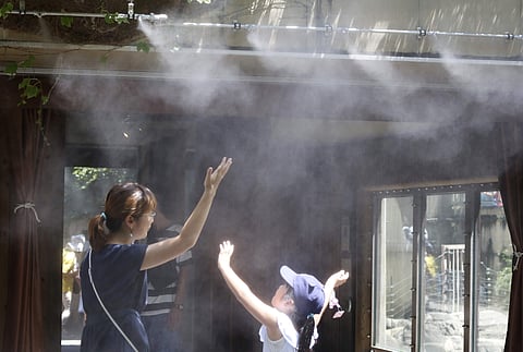 Visitors walk under a water mist to cool themselves in the scorching heat at a zoo in Tokyo. (Photo | AP)