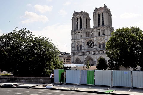 Workers install high fences on a bridge around Notre Dame cathedral in Paris (Photo | AP)