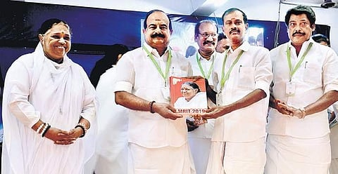 Minister K C Karuppannan releasing a souvenir and giving the first copy to Minister Sevvoor S Ramachandran as Mata Amritanandamayi looks on, during the Brahmasthanam Mahotsavam in city | D SAMPATHKUMAR