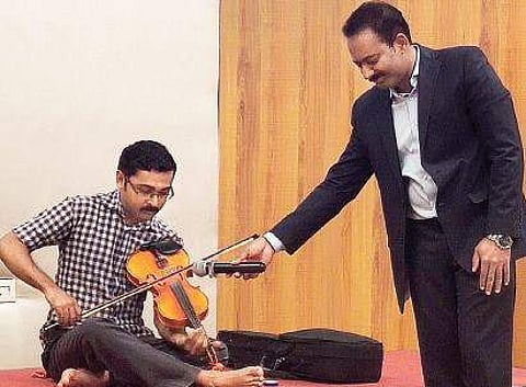 Vinod Haridas playing violin at the press meet held in Kochi