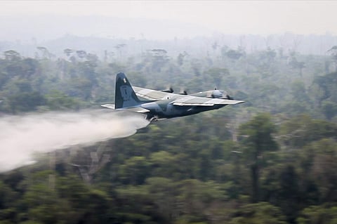 A C-130 Hercules aircraft dumps water to fight fires burning in the Amazon rainforest, in Brazil, Saturday. (Photo | AP)