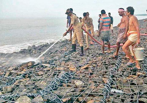 Officials and villagers dousing fire in geo-synthetic tubes at Pentha in Kendrapara district | Express